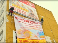 Montáž reklamnej plachty na stenu budovy pomocou horolezeckej techniky